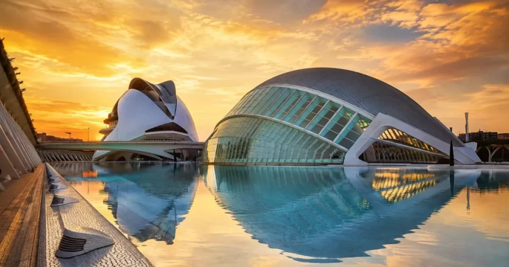 Ciudad de las Artes y las Ciencias de Valencia con el Hemisferic y el Palacio de las Artes Reina Sofía al amanecer dorado reflejándose en el estanque