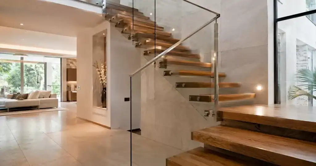 Escalera interior moderna con peldanos flotantes de madera y barandilla de vidrio y acero