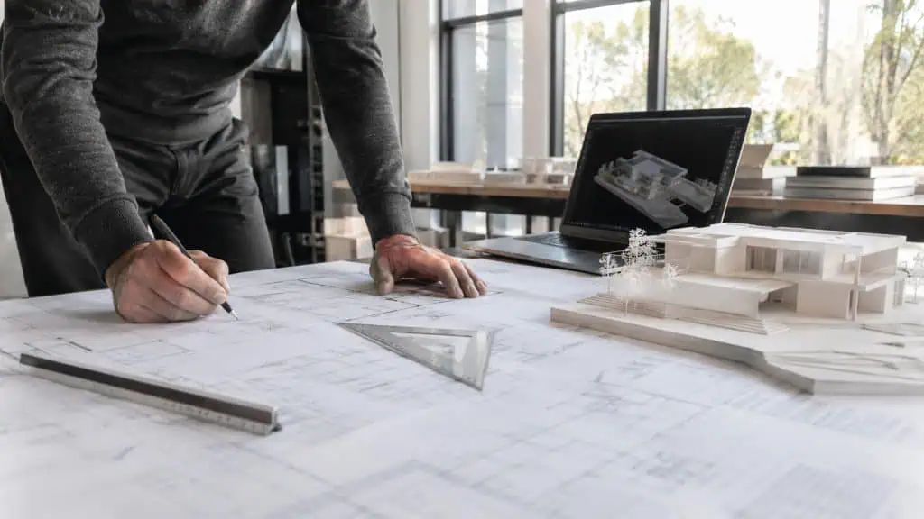 Arquitecto en Zaragoza revisando planos de vivienda unifamiliar junto a una maqueta a escala en su estudio de arquitectura