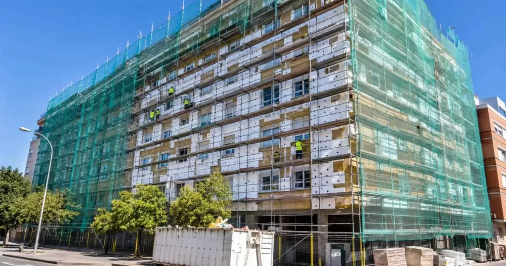 Bloque de viviendas en rehabilitación energética integral con andamio completo y aislamiento de fachada, eficiencia energética