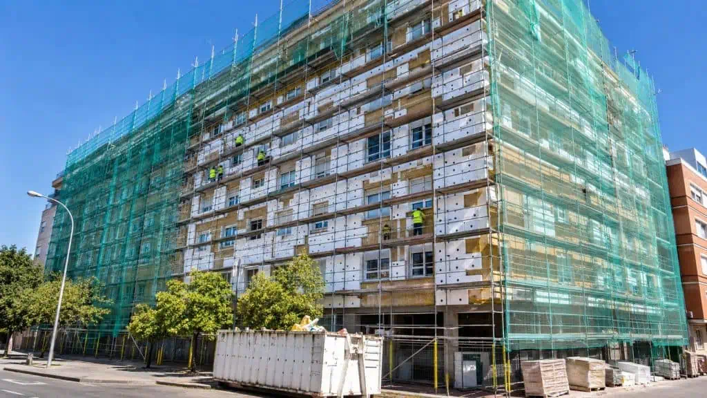 Bloque de viviendas en rehabilitación energética integral con andamio completo y aislamiento de fachada, eficiencia energética